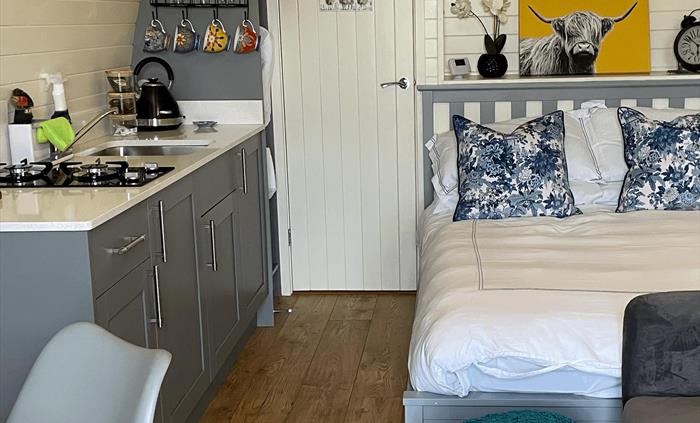 Showing inside of the luxury glamping pod with bed, sofa and kitchenette